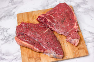 seasoned raw steaks on a board.