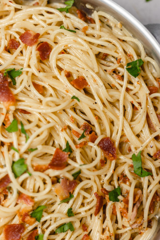 bacon crumbled over a pan of spaghetti.