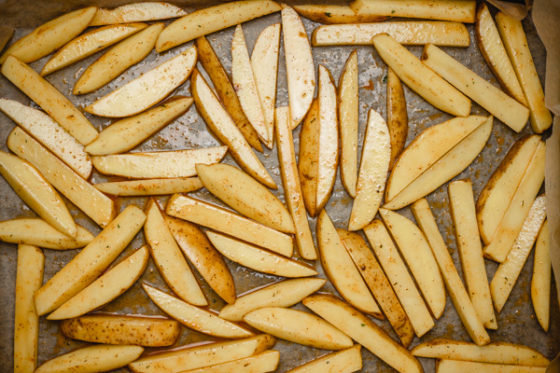 sliced potatoes lined on a lined baking tray.