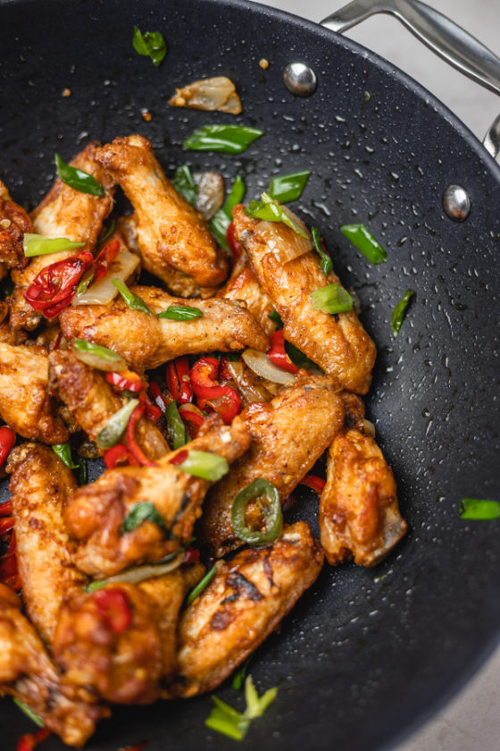 chicken wings and peppers in a wok.