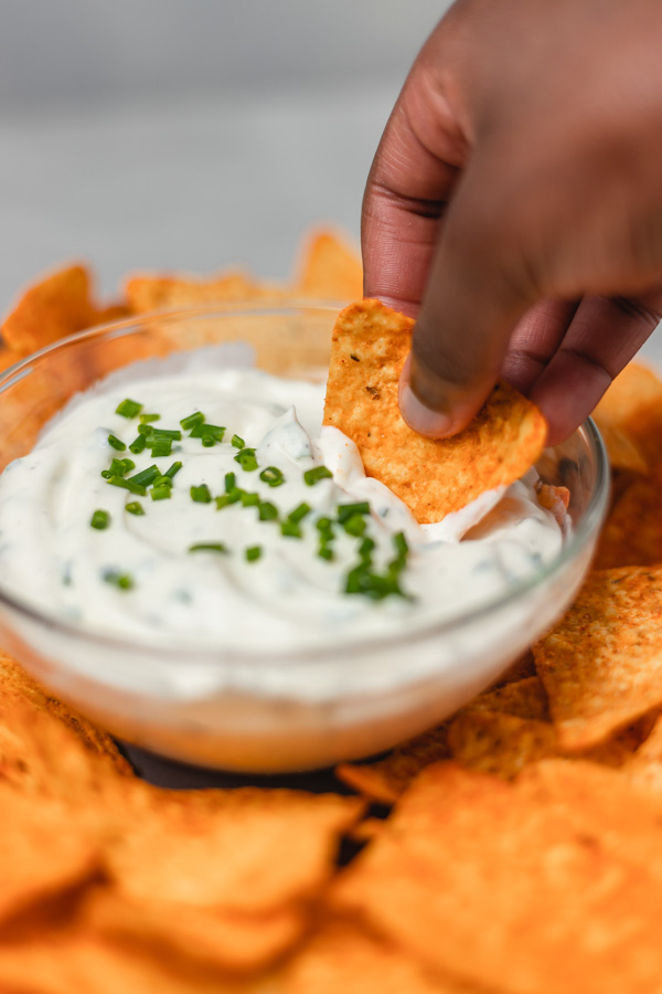 a hand dipping a chip in a bowl of dip.
