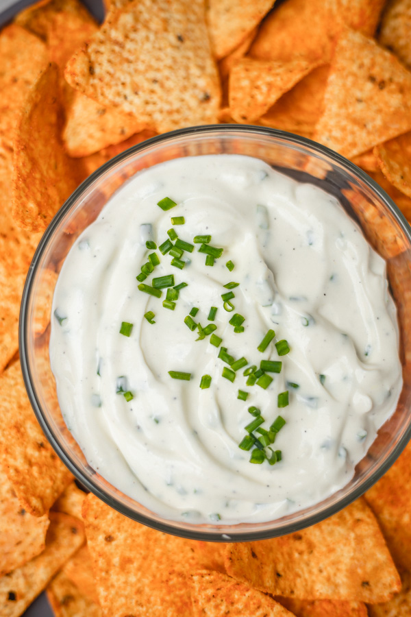 a bowl of dip placed on a plate of chips.
