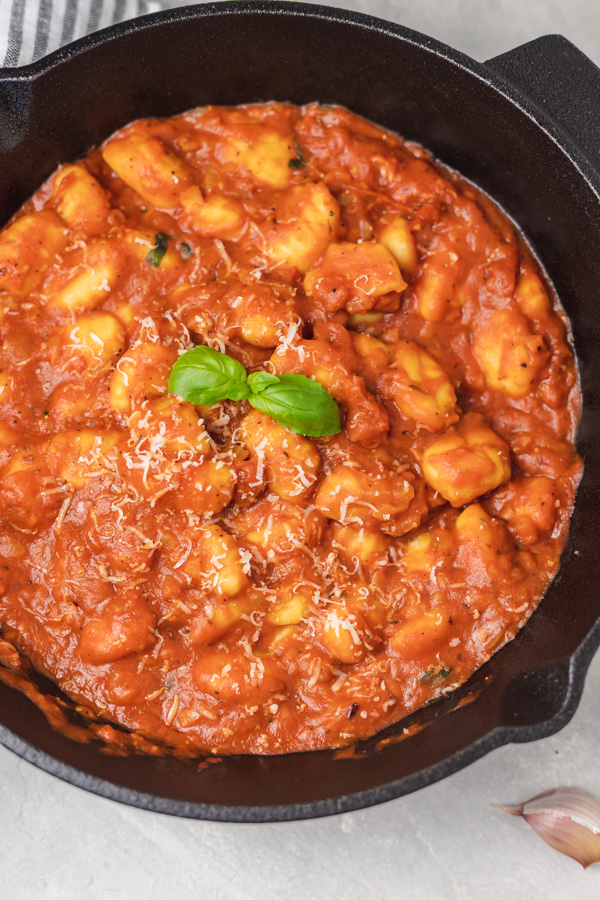 a cast iron with cooked gnocchi garnished with fresh basil 