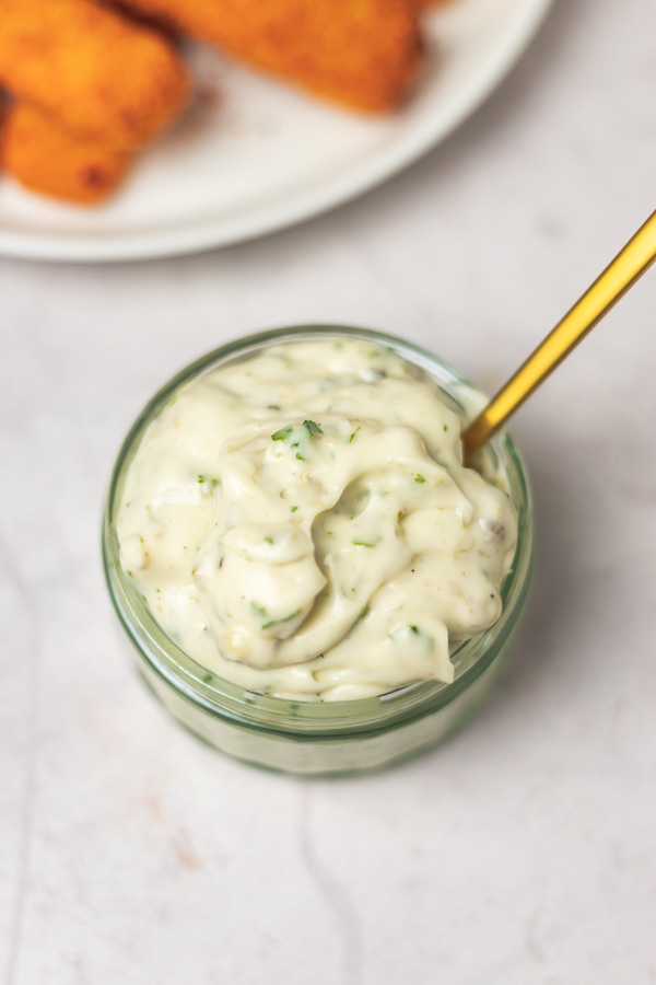 a small pot of tartare sauce with a spoon.