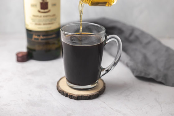 pouring whiskey into coffee.