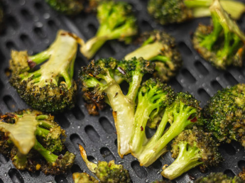 cooked broccoli florets in the air fryer basket.
