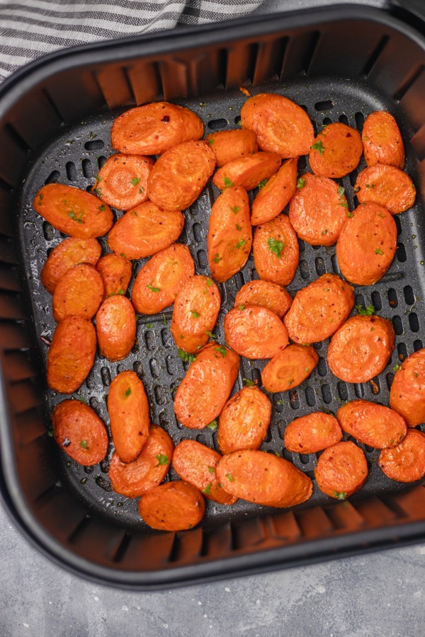 cooked carrots in an air fryer basket.