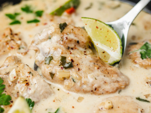 a skillet of coconut chicken thighs in white sauce.