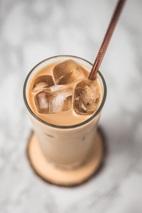 the top view of iced coffee in a glass with a metal straw.