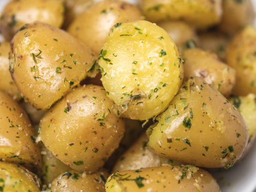 herby and buttery boiled potatoes on a plate.