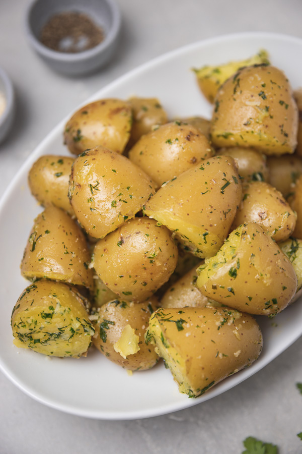 herby baby potatoes sliced into halves on a plate.
