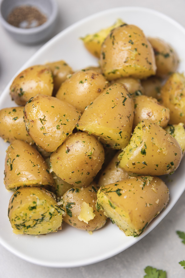 a platter of buttery boiled potatoes with herbs.