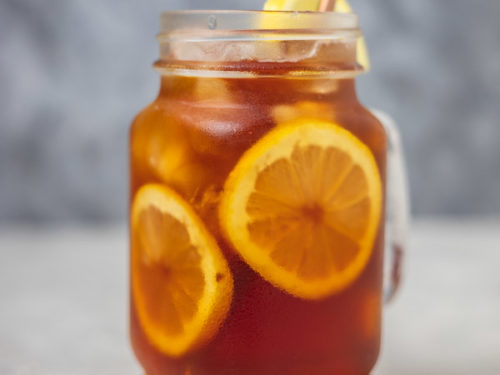 a glass of iced lemon tea with a straw.
