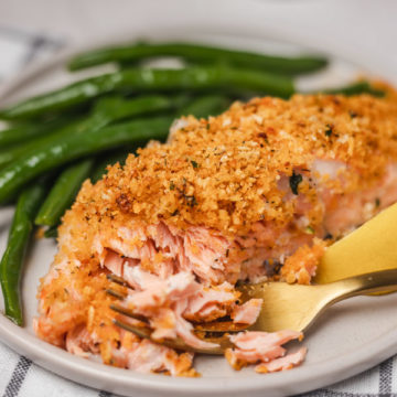 parmesan crusted salmon on a plate with sauteed green beans.