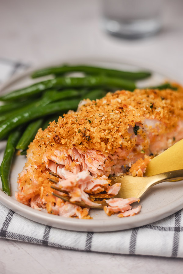 a plate of crusted salmon flaked with a fork served with green beans.