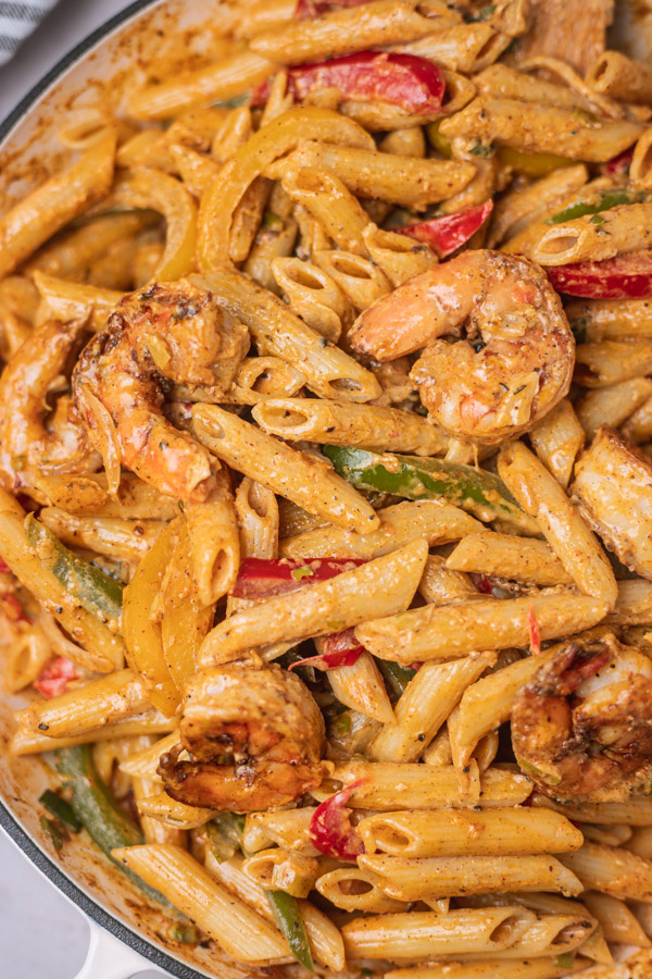 a close shot of a colourful creamy pasta with shrimps and bell peppers.