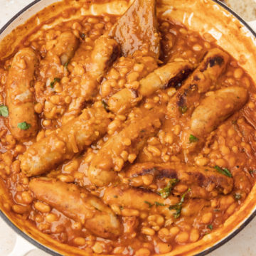 sausage and beans casserole with a wooden ladle.