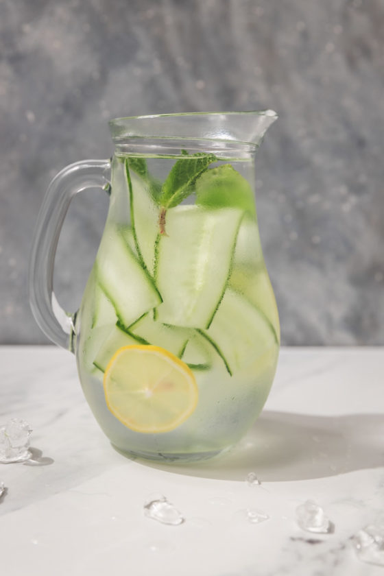a pitcher filled with water, cucumber ribbon and lemon slices.