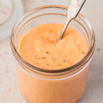 creamy bang bang sauce in a jar with a spoon.