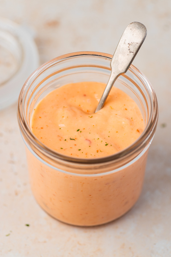 bang bang sauce in a glass jar with a spoon.