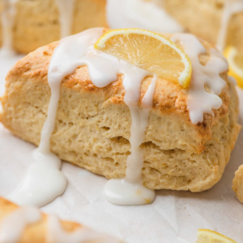 a close shot of lemon scone with icing and a slice of lemon on the top.