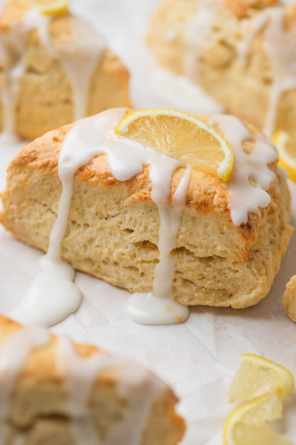 a close shot of lemon scone with icing and a slice of lemon on the top.