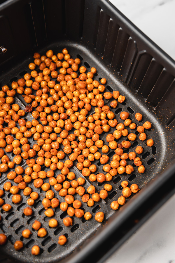 cooked chickpeas in an air fryer basket.