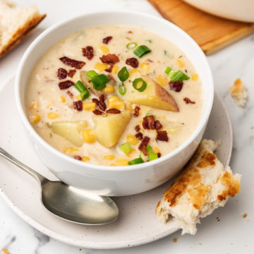 a bowl of corn chowder served with acrusty bread.