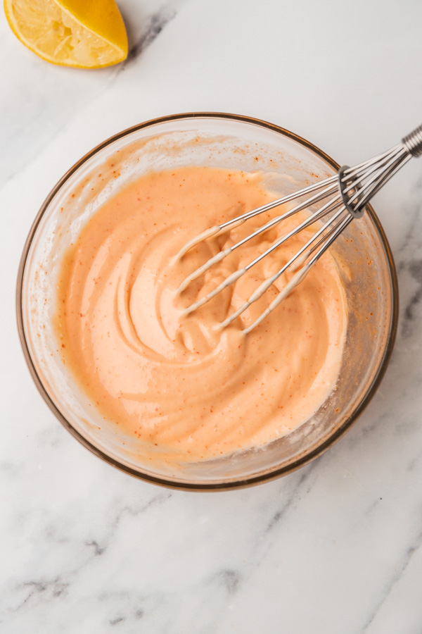 a whisk in a bowl of sauce.