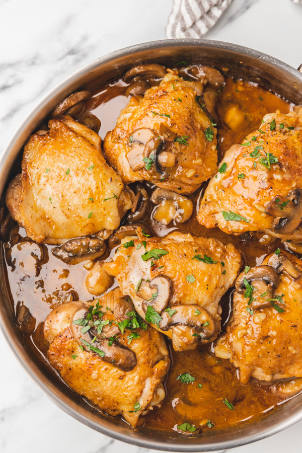 six chicken thighs in mushroom sauce in a skillet.