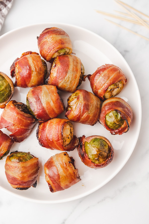 bacon wrapped brussels sprouts on a white plate.