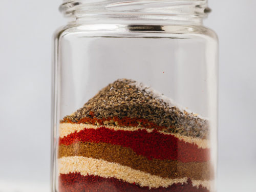 different spices in a glass jar on a counter.
