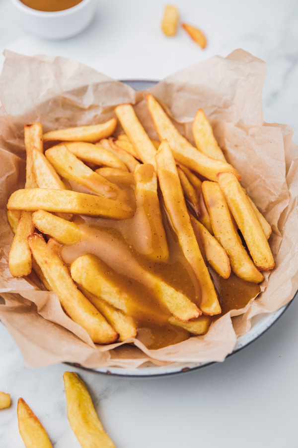 a bowl of fries slatered with chinese curry sauce.
