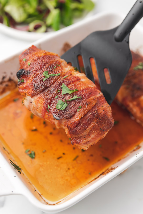 bacon wrapped chicken on a spatula turner.