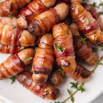 pig in blankets with thyme on a plate.
