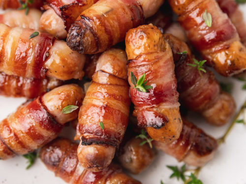 pig in blankets with thyme on a plate.