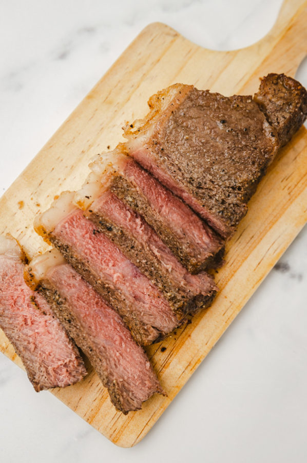 cloce shot of sliced steak on a chopping board.
