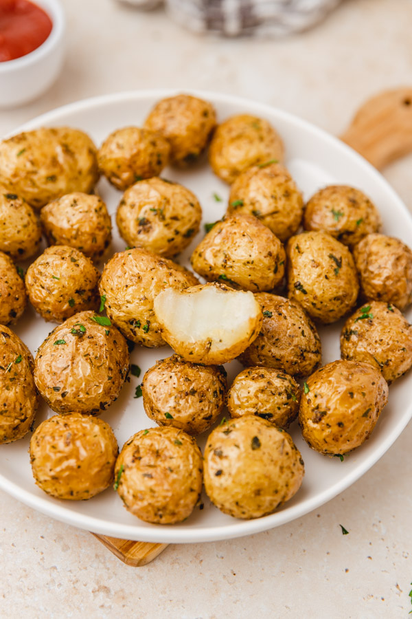 a plate of roasted baby potatoes with one biten potato.