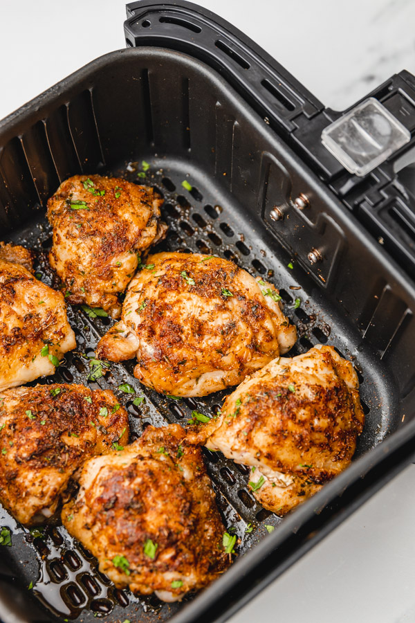 six cooked golden chicken thighs in a basket.