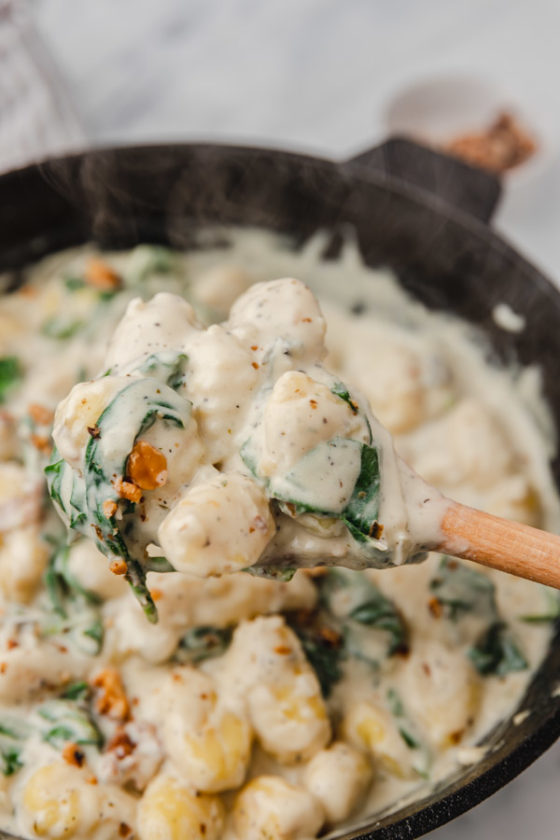 ladle of creamy gnocchi with spinach.