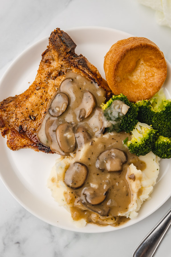 mushroom gravy doused on mahed potatoes and pork chops, broccoli and yorkshire pudding.