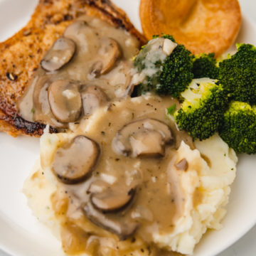 a plate of mashed potatoes, pork chops and mushroom gravy.