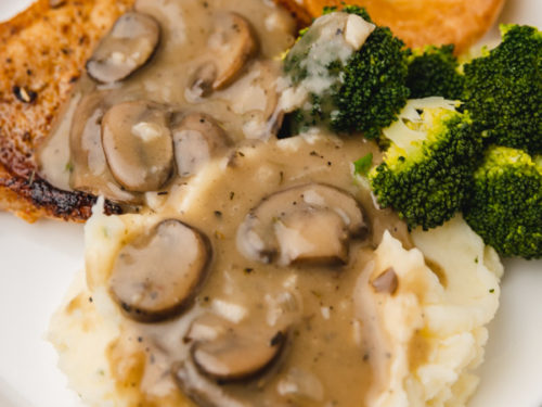 a plate of mashed potatoes, pork chops and mushroom gravy.