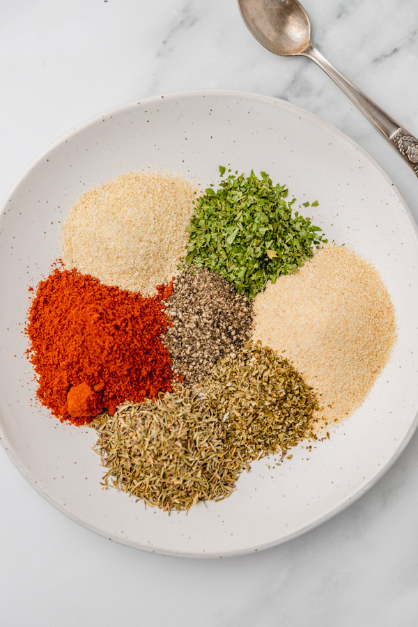 seven different types of spices and herbs on a plate.