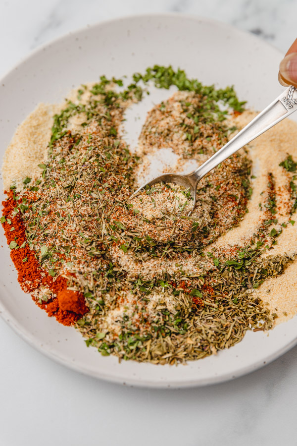 a hand mixing spices in a plate.