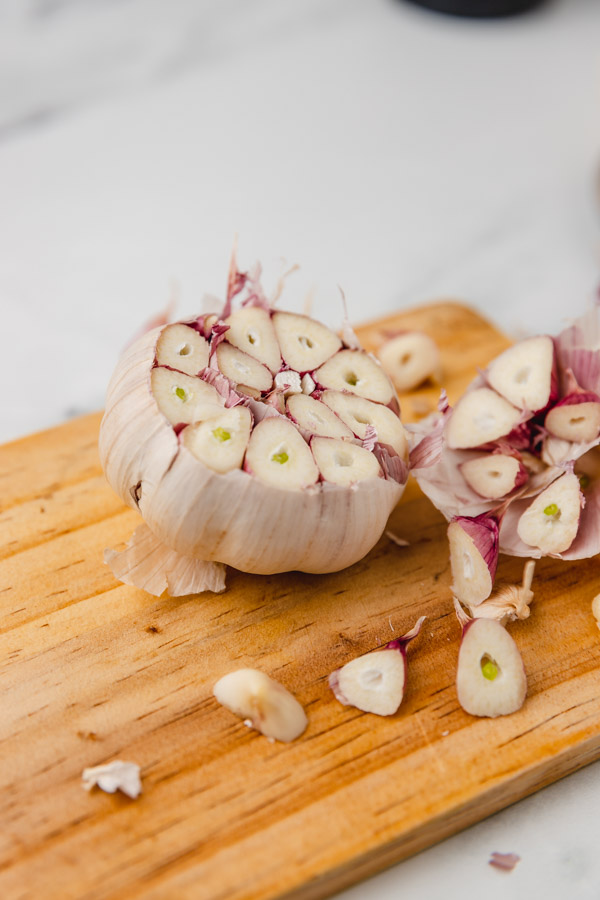 fresh head of garlic with  the top cut off so that it is exposed on a chopping board.