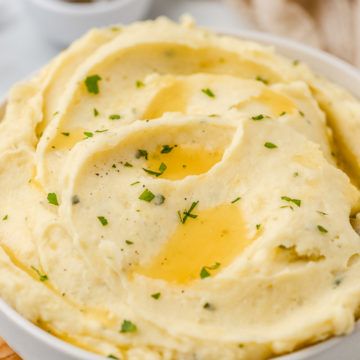a bowl of mashed potatoes drizzeld with melted butter.