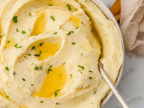 a bowl of creamy mashed potatoes with a big serving spoon.