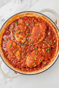 a pan with chicken breast neastled in tomato sauce