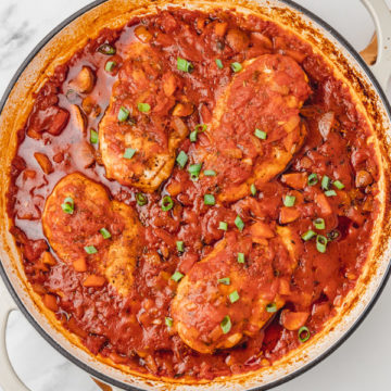 a pan with chicken breast neastled in tomato sauce